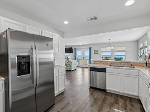 A modern kitchen with stainless steel appliances, white cabinetry, and a view to the outside. - Frisco Flats by Miss Kitty’s (Rockport)