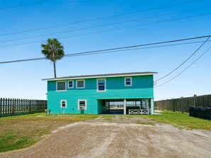 A two-story house with a garage, surrounded by a wooden fence, under clear skies. - Frisco Flats by Miss Kitty’s (Rockport)