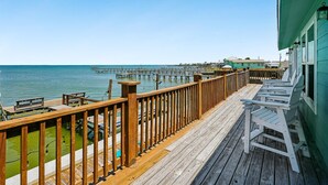 A wooden deck with a view of the ocean and a pier in the background.
