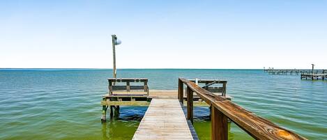 A wooden pier extending into calm waters with a bench and a lamp post.