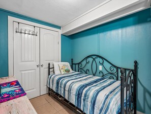 A bedroom with a bed, a door, and a wall painted in a teal color. - Frisco Flats by Miss Kitty’s (Rockport)