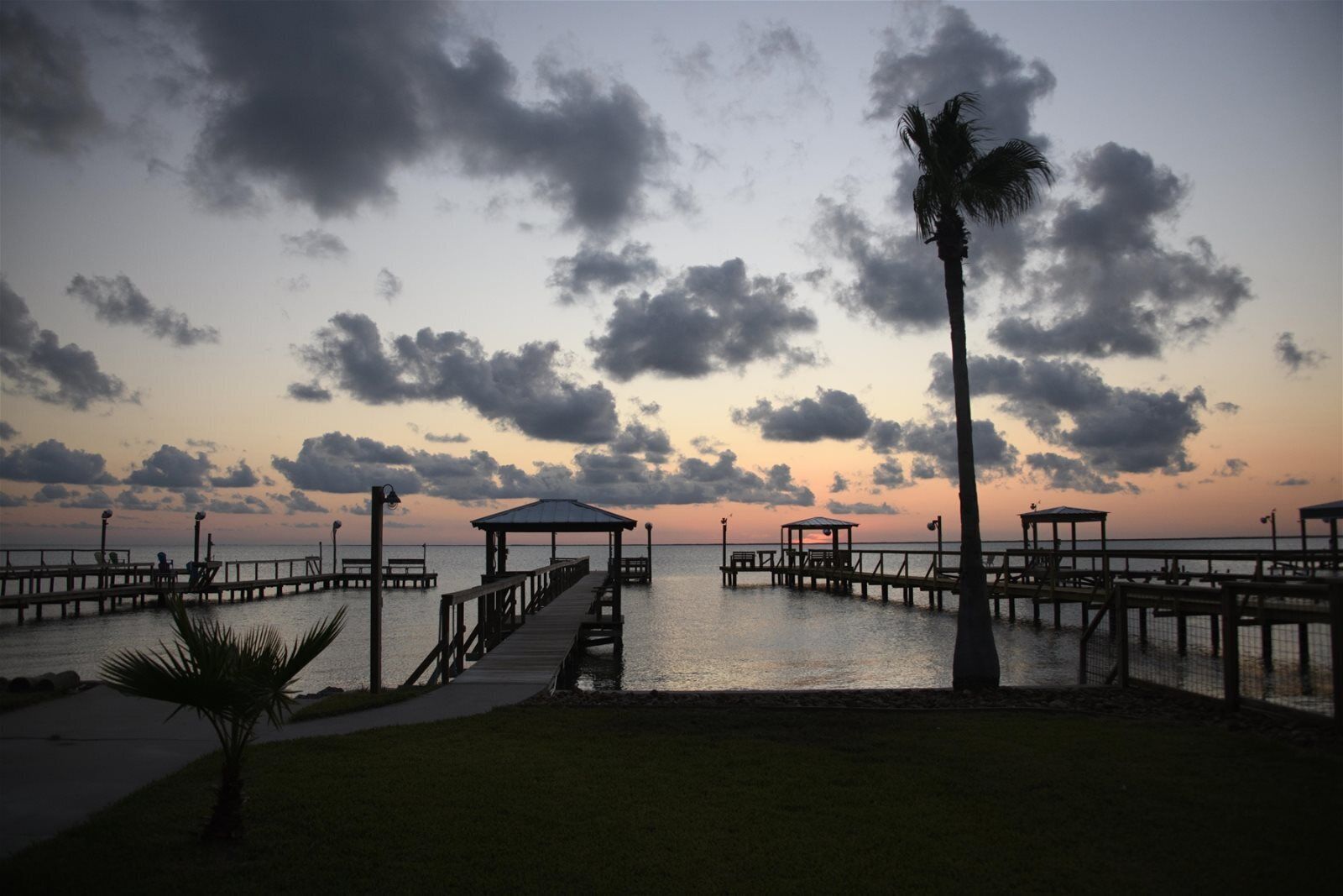 A pier extending into calm waters with a sunset in the background.