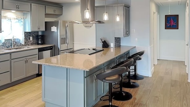 A modern kitchen with a central island, bar stools, and pendant lighting. - Trout Tank by Miss Kitty’s (Rockport)