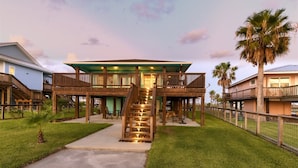 A two-story wooden building with a central staircase, outdoor seating area, and a fenced yard. - Trout Tank by Miss Kitty’s (Rockport)