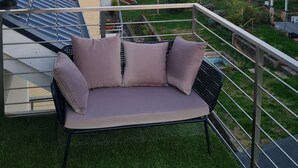 A balcony with a beige sofa, a satellite dish, and a view of a town with houses and a tower. - Luxurious apartment (new build) with feel-good guarantee.... Temporary living (Ispringen)