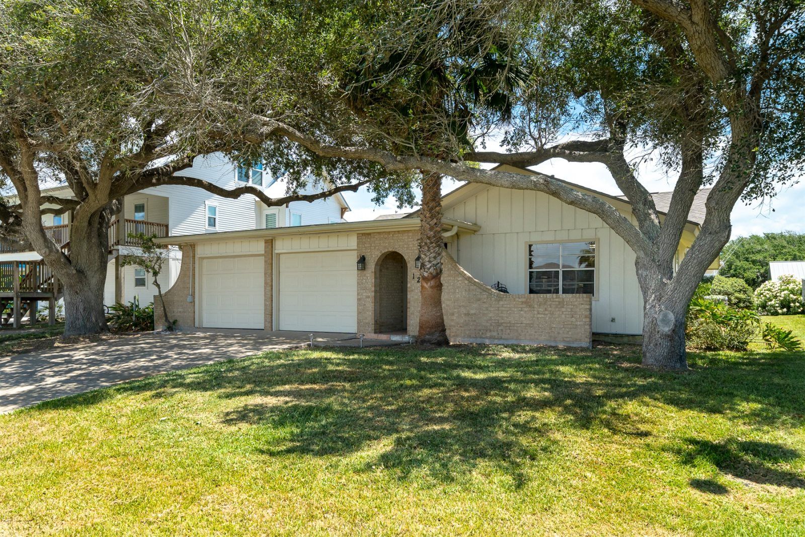 A two-story house with a garage, a brick entrance, and a large tree in front.