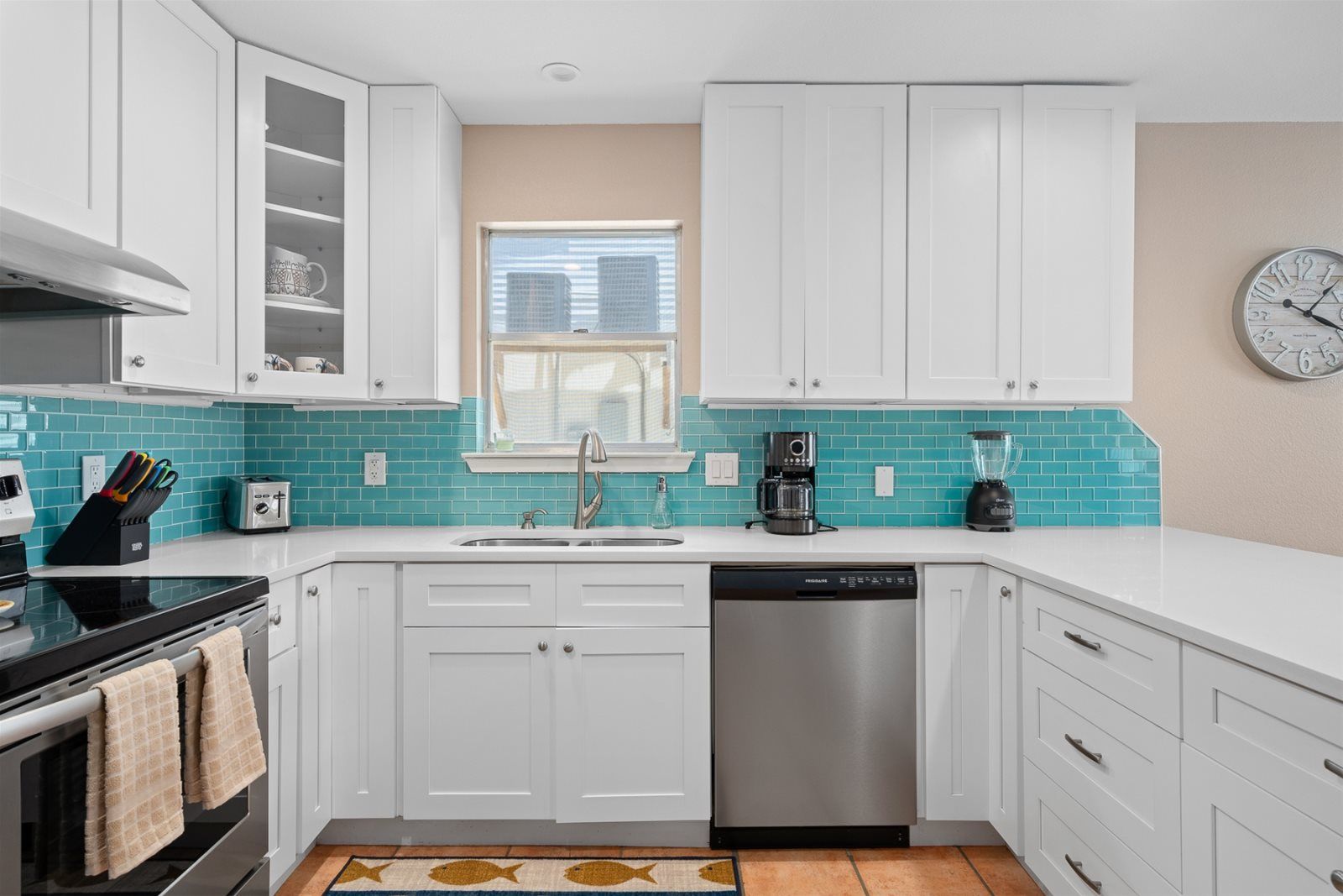 A modern kitchen with white cabinets, a dishwasher, a coffee maker, and a blender.