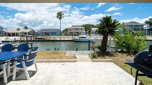 A waterfront patio with a view of a marina, including boats and houses. - Gone Coastal by Miss Kitty’s (Rockport)