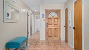 A hallway with a wooden door, a bench, and a sign that says "WELCOME". - Gone Coastal by Miss Kitty’s (Rockport)