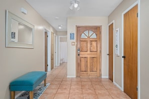 A hallway with a wooden door, a bench, and a sign that says "WELCOME". - Gone Coastal by Miss Kitty’s (Rockport)