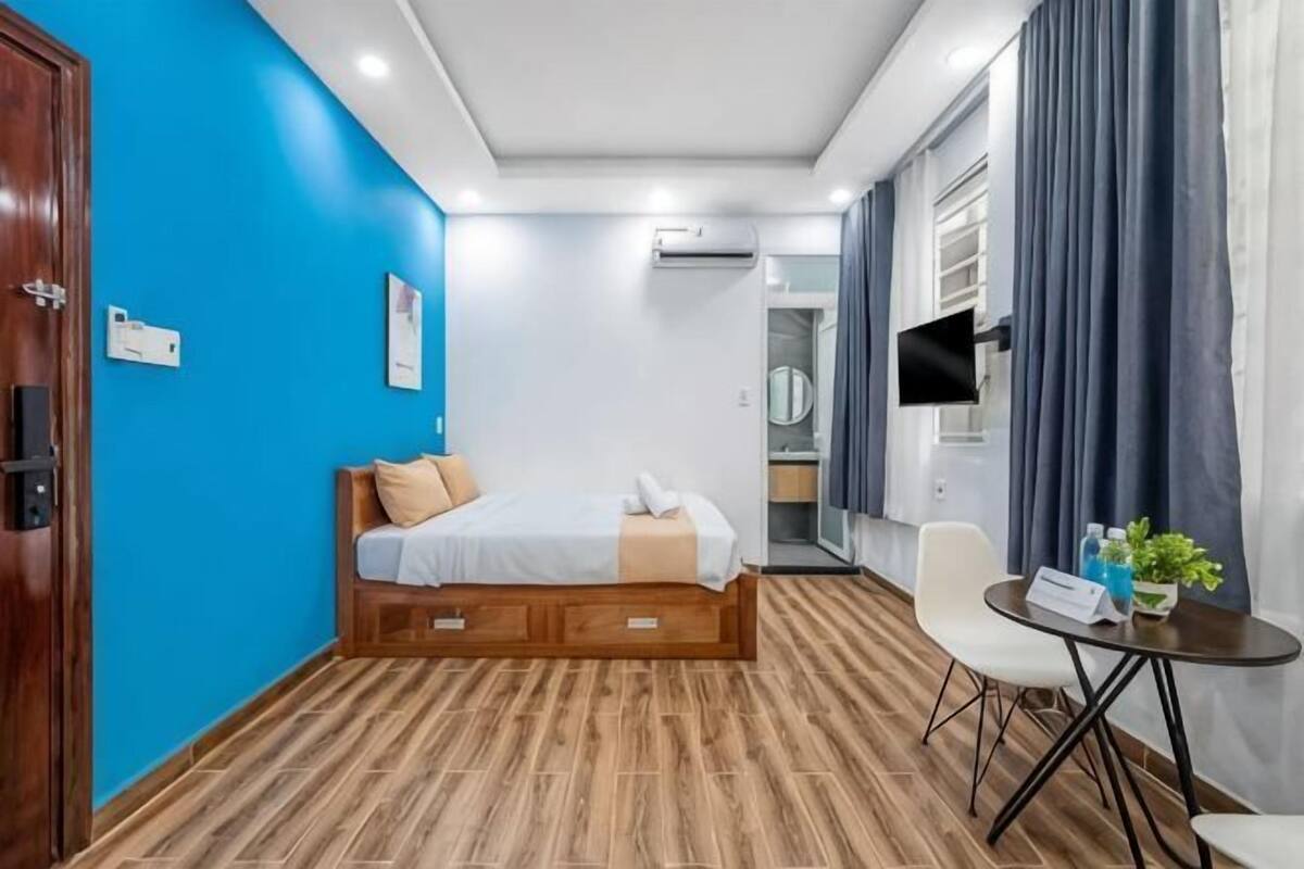 A bedroom with a bed, a desk, a chair, and a TV.