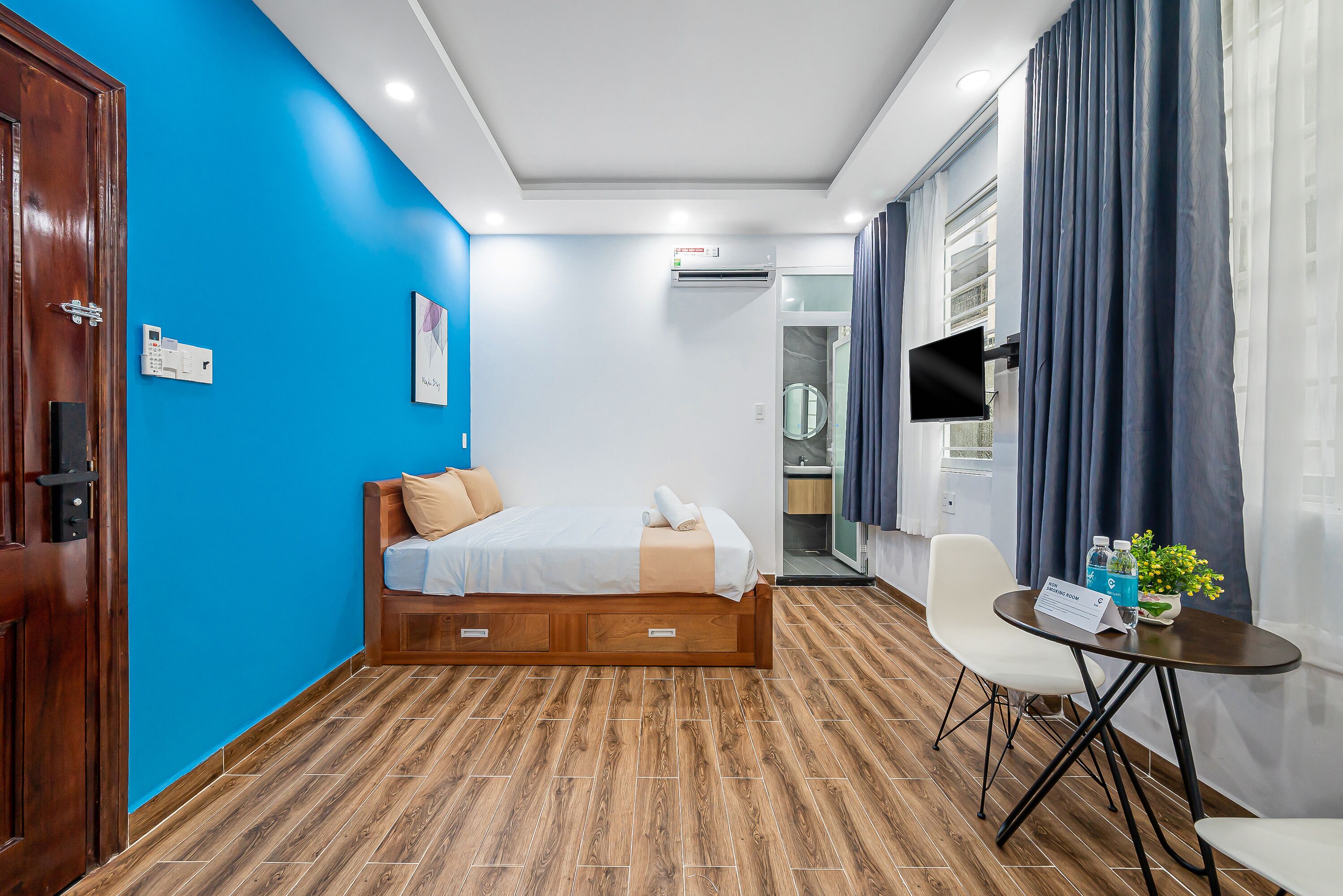 A hotel room with a bed, a desk, a chair, a TV, and a window with curtains.