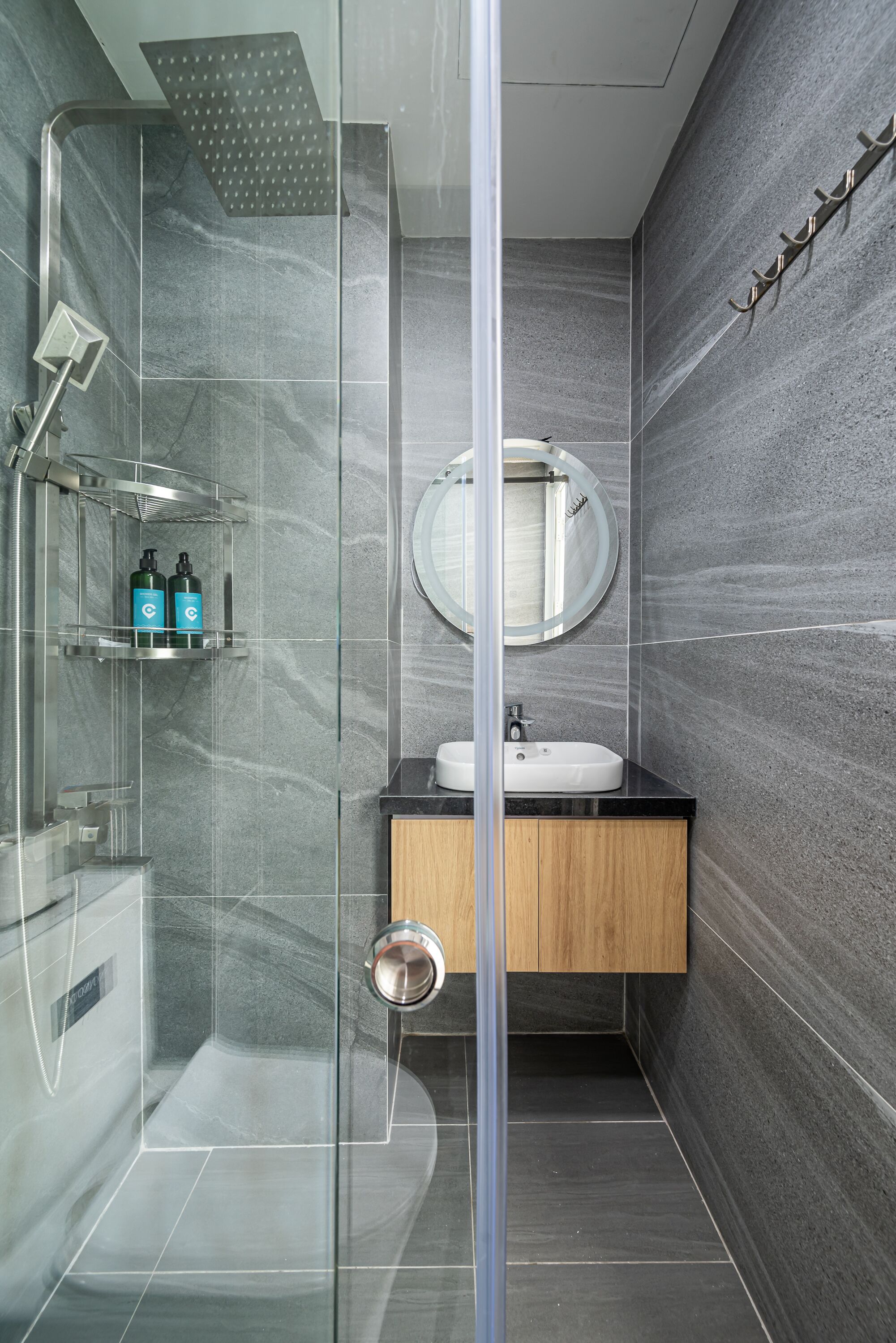 Une salle de bain moderne avec une douche à parois de verre, un meuble-lavabo en bois et un pare-baignoire en marbre.