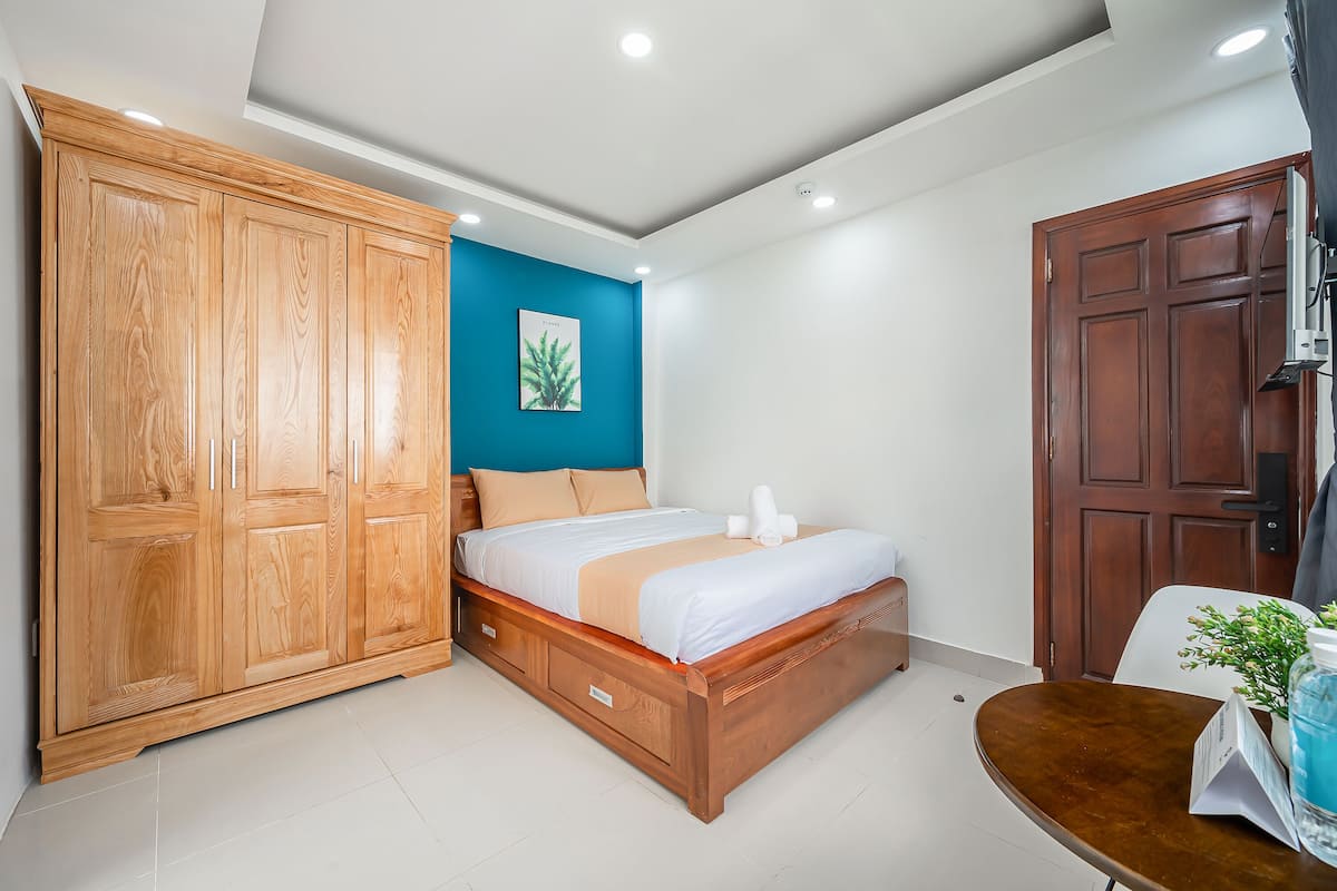 A bedroom with a wooden bed, a wardrobe, a blue accent wall, and a door.