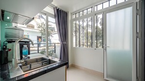 Una cocina con un lavamanos, dispensador de agua y una ventana con cortinas.
