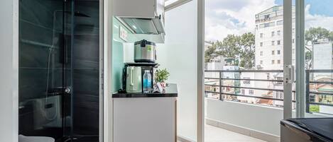 A modern bathroom with a glass shower enclosure, a toilet, and a sink with a kettle and water bottle on the counter.
