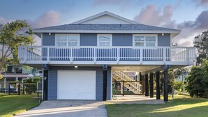 A two-story house with a balcony, a garage, and a staircase leading to the upper floor. - Bayside Blessing by Miss Kitty’s (Rockport)