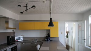 Een moderne keuken met een centraal eiland, een ingebouwde oven en een koffieapparaat.