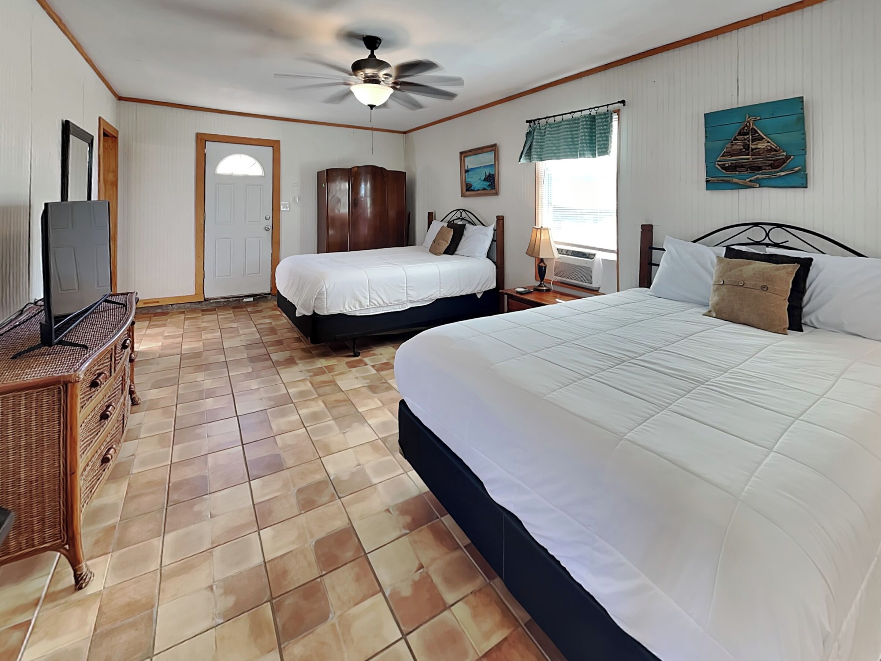 A bedroom with two beds, a ceiling fan, a dresser, and a painting on the wall.