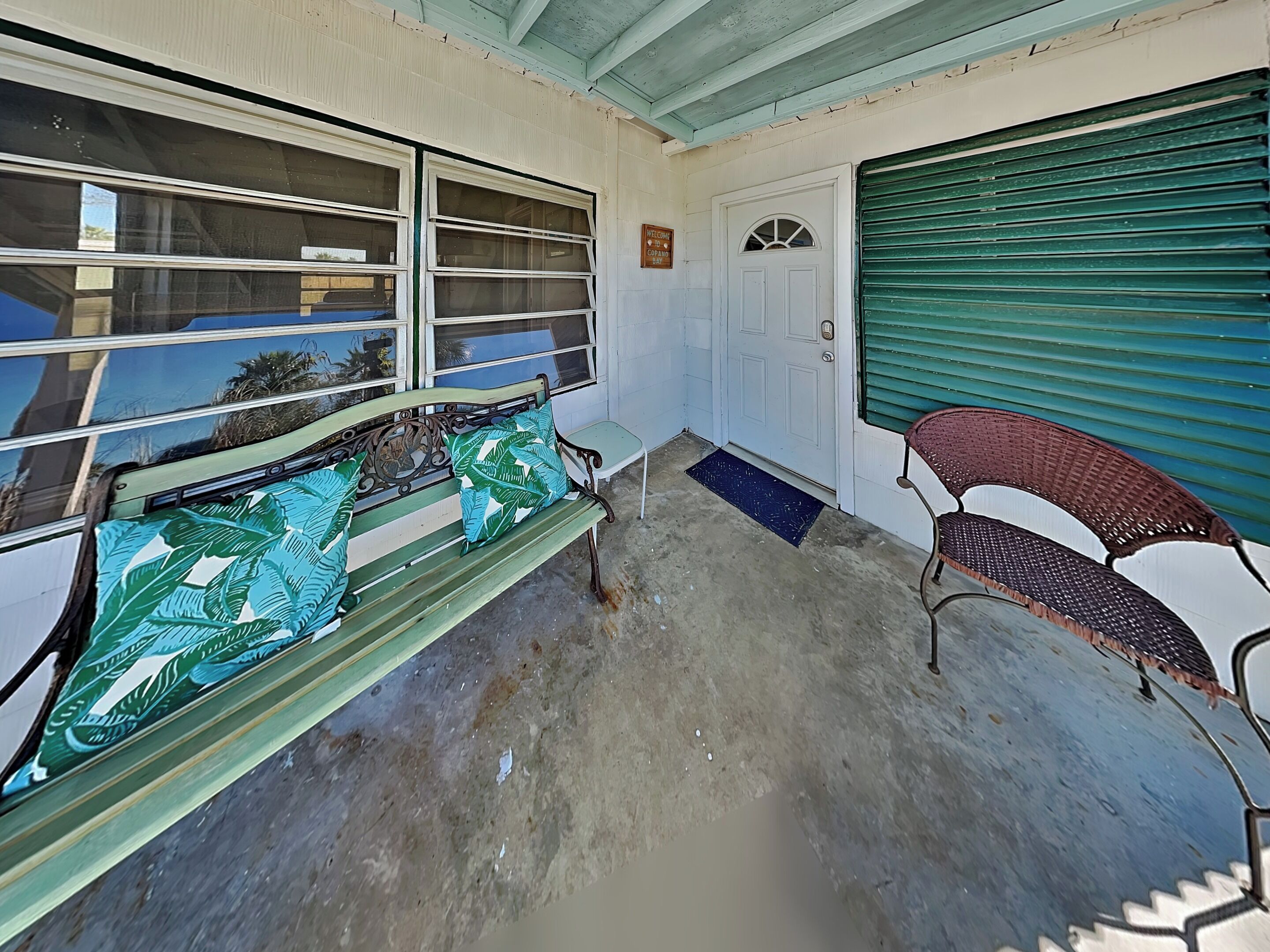 Un porche con un banco, una silla, una puerta y una ventana con vistas.