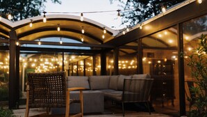 An outdoor seating area with a wooden deck, cushioned seating, and string lights. - 2 mi from LSU! MCM Masterpiece - Sleeps 10 (Baton Rouge)