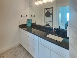 Une salle de bain moderne avec un grand miroir, un lavabo et un lave-linge encastré.