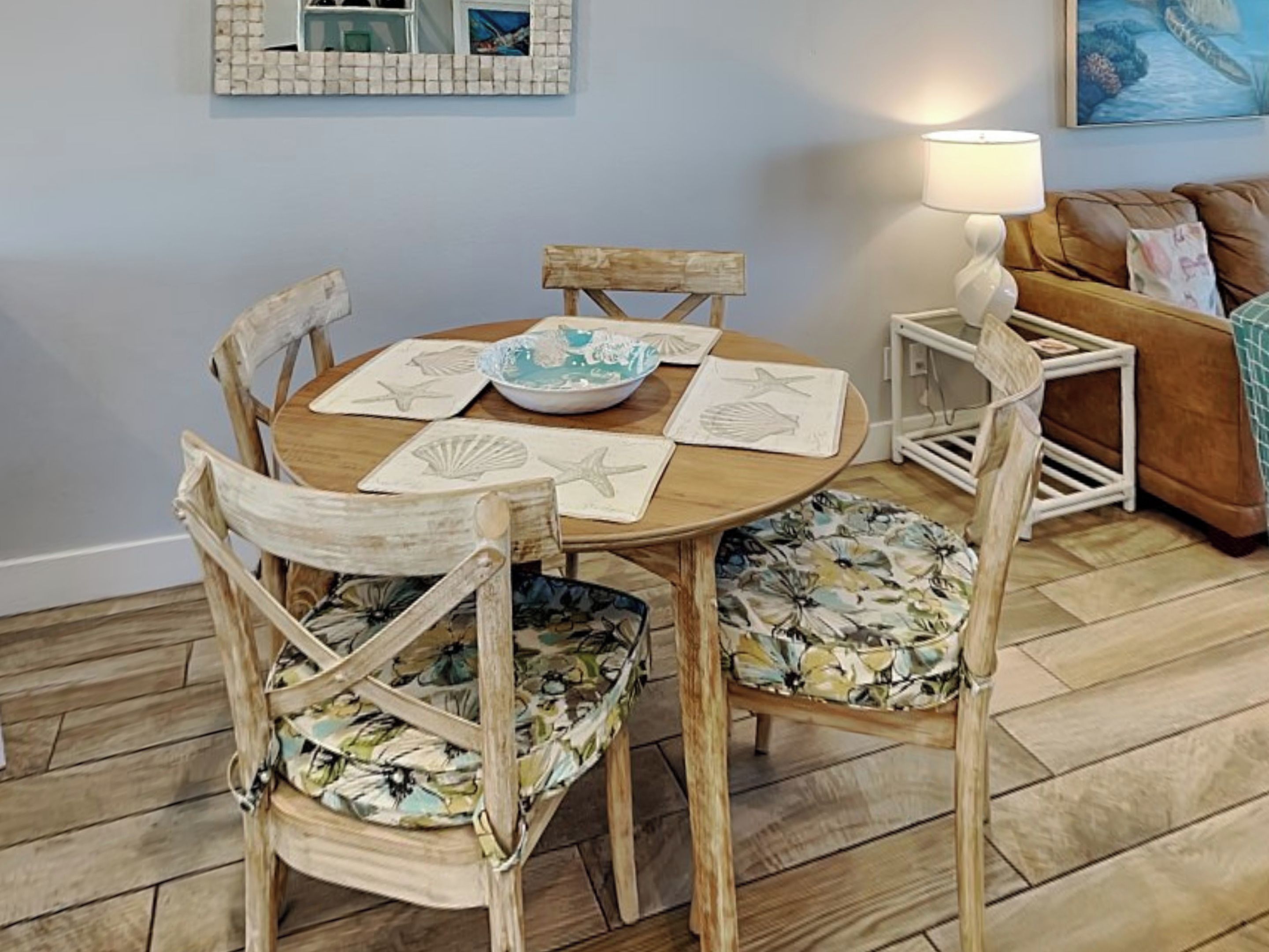 A round wooden table with a floral chair cushion, a bowl, and starfish-shaped placemats.