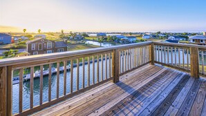 Een houten terras met uitzicht op een woongebied en water.