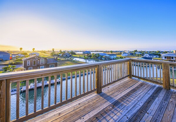A wooden deck with a view of a residential area and water.
