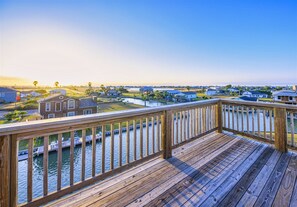 A wooden deck with a view of a residential area and water.