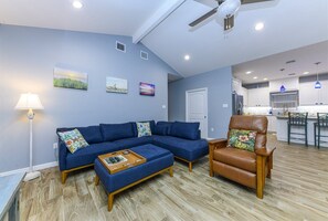 A living room with a sectional sofa, a brown leather armchair, and a coffee table.