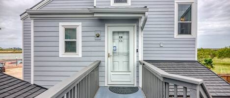 Una casa de dos pisos con puerta principal, un pequeño porche y una puerta de garaje visible.
