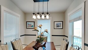 A dining room with a wooden table, chairs, hanging pendant lights, and framed artwork on the walls. - Casa Del Sol by Miss Kitty’s (Rockport)