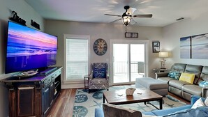 A living room with a television, a ceiling fan, a sofa, a coffee table, and a patterned rug. - Casa Del Sol by Miss Kitty’s (Rockport)