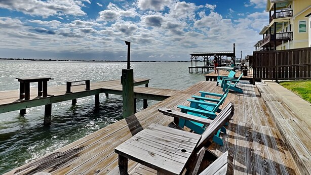 A wooden pier extending into a body of water with a clear sky and clouds. - Casa Del Sol by Miss Kitty’s (Rockport)