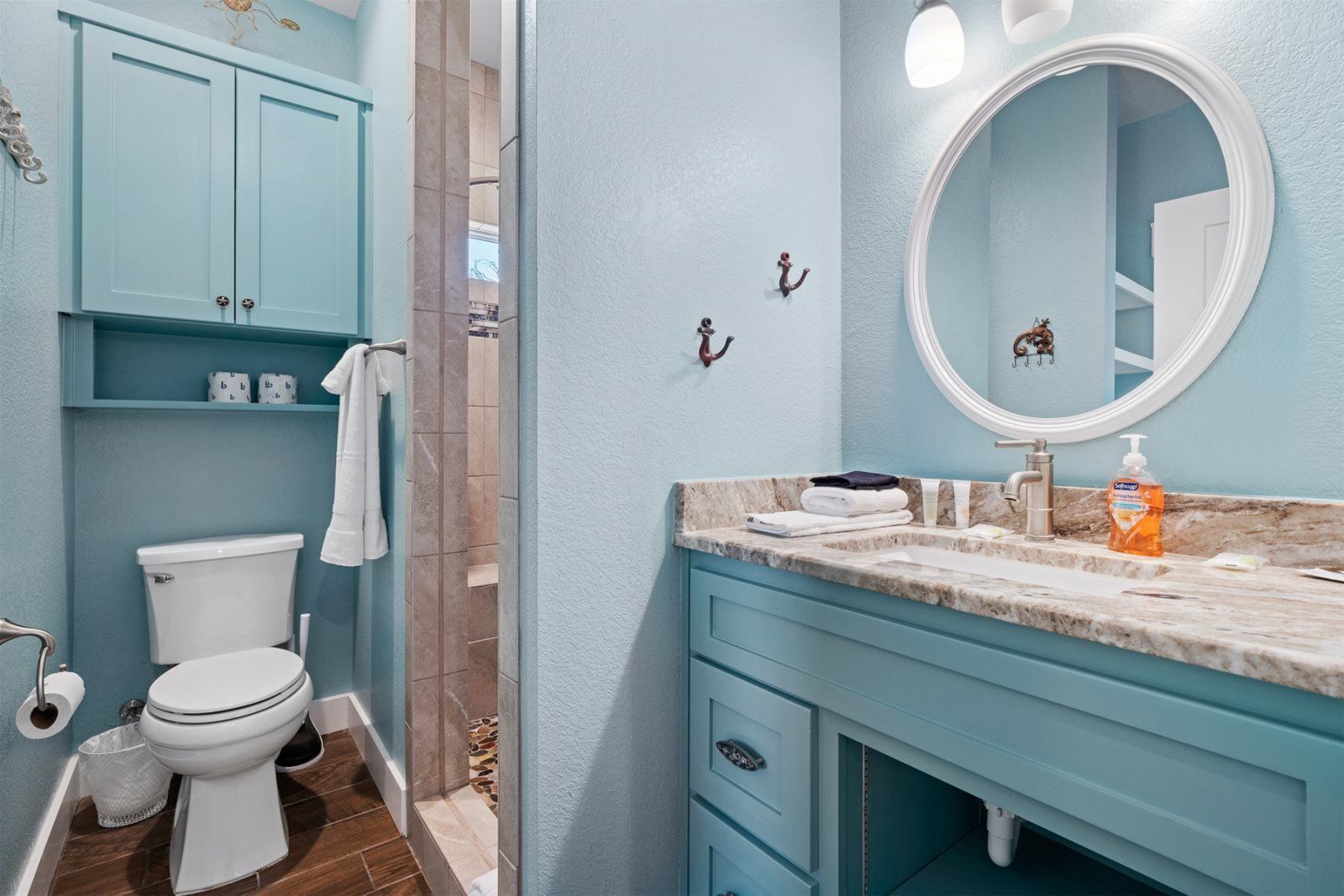 A bathroom with a toilet, sink, and vanity. There are towels and toiletries on the counter.