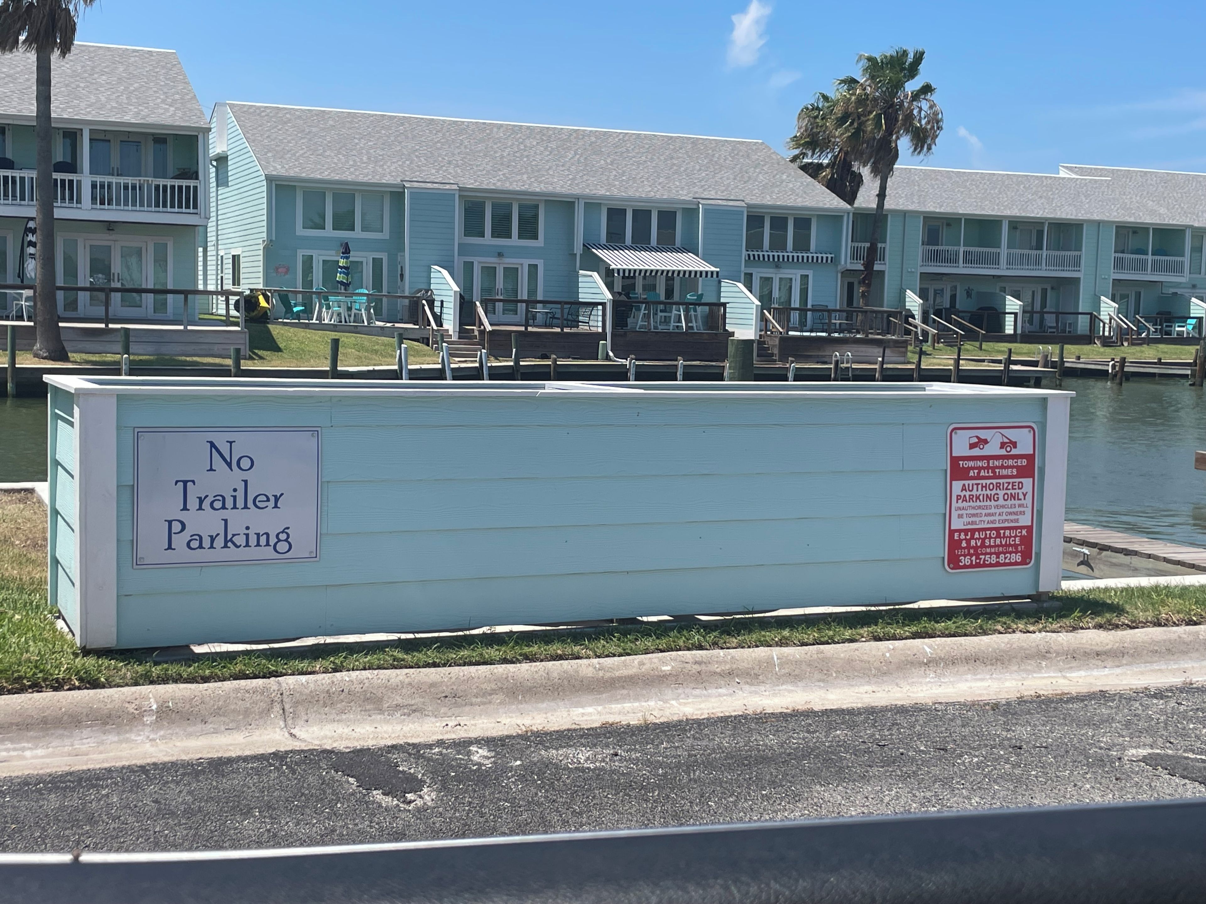 A no trailer parking sign near a waterfront property with a dock and boats.