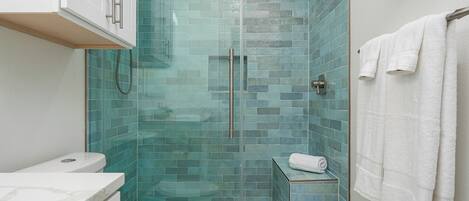 A bathroom with a glass-enclosed shower, a white toilet, and a towel rack.