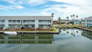 Un hôtel situé au bord de l’eau, doté d’un quai, d’un bateau et d’une étendue d’eau calme dans laquelle se reflètent les bâtiments.
