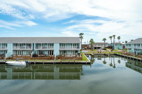 A waterfront hotel with a dock, a boat, and a calm water body reflecting the buildings. - Coastal Bliss by Miss Kitty’s (Rockport)