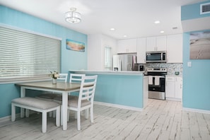 A modern kitchen with white cabinets, stainless steel appliances, and a blue accent wall.