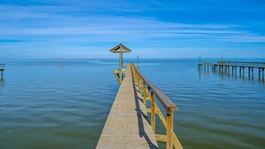 Un muelle de madera que se adentra en aguas tranquilas bajo un cielo despejado.