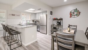 A modern kitchen with a central island, bar stools, a dining table with chairs, and a coffee station. - The Perfect Tucson Townhome in Catalina Foothills (Tucson)