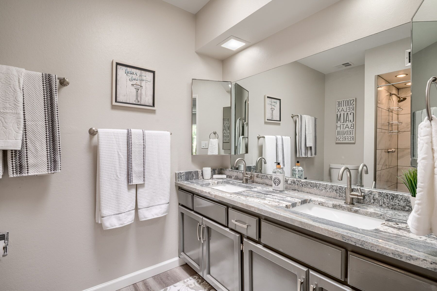 Un baño moderno con dos lavamanos, un espejo grande y varias toallas.