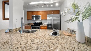 A modern kitchen with granite countertops, stainless steel appliances, wooden cabinets, and a central island. - Lovely 2-Bedroom Apartment in Scottsdale! (Scottsdale)