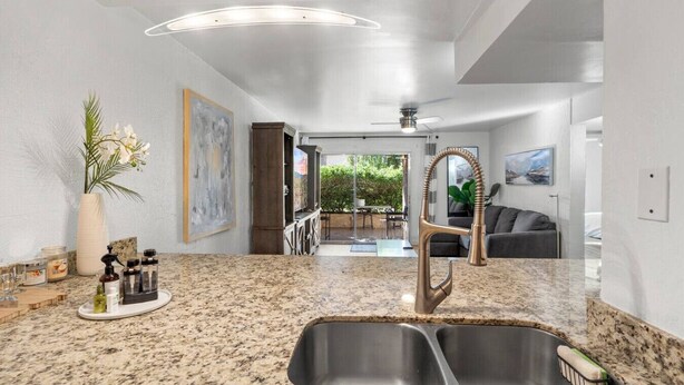 A modern kitchen with granite countertops, stainless steel sink, and pendant lighting. - Lovely 2-Bedroom Apartment in Scottsdale! (Scottsdale)