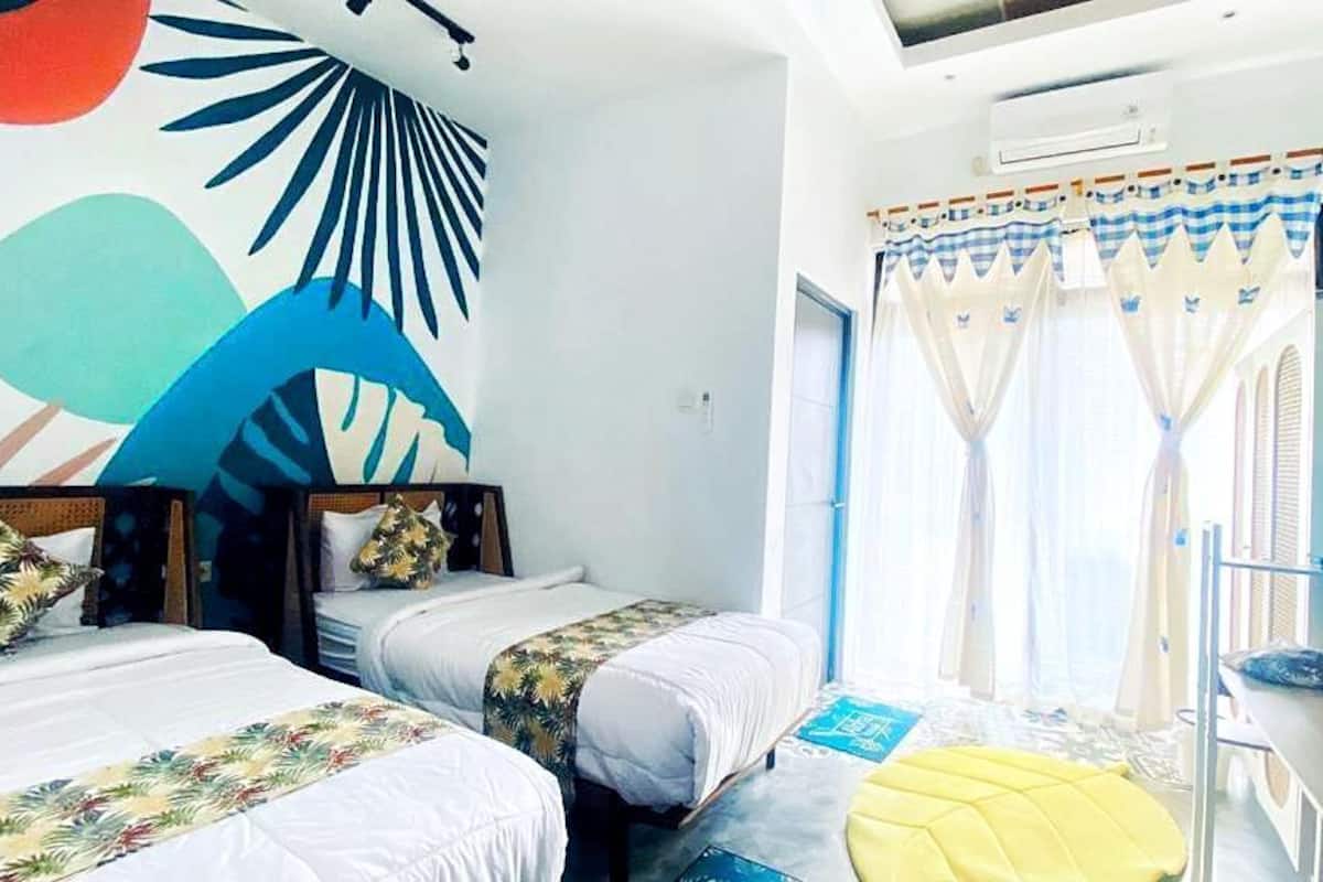 A room with two beds, a TV, and a window with curtains.
