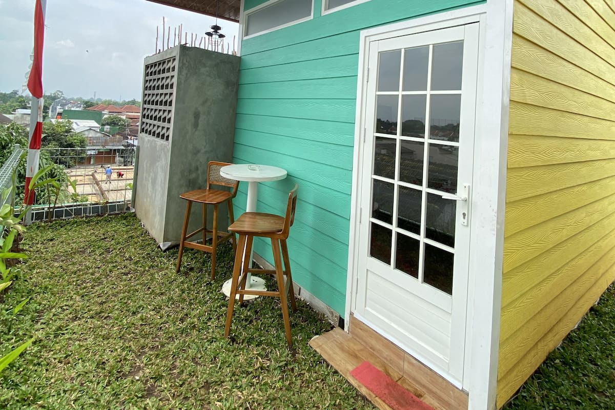 A small patio area with a table and chairs, a concrete structure, and a view of the surrounding area.