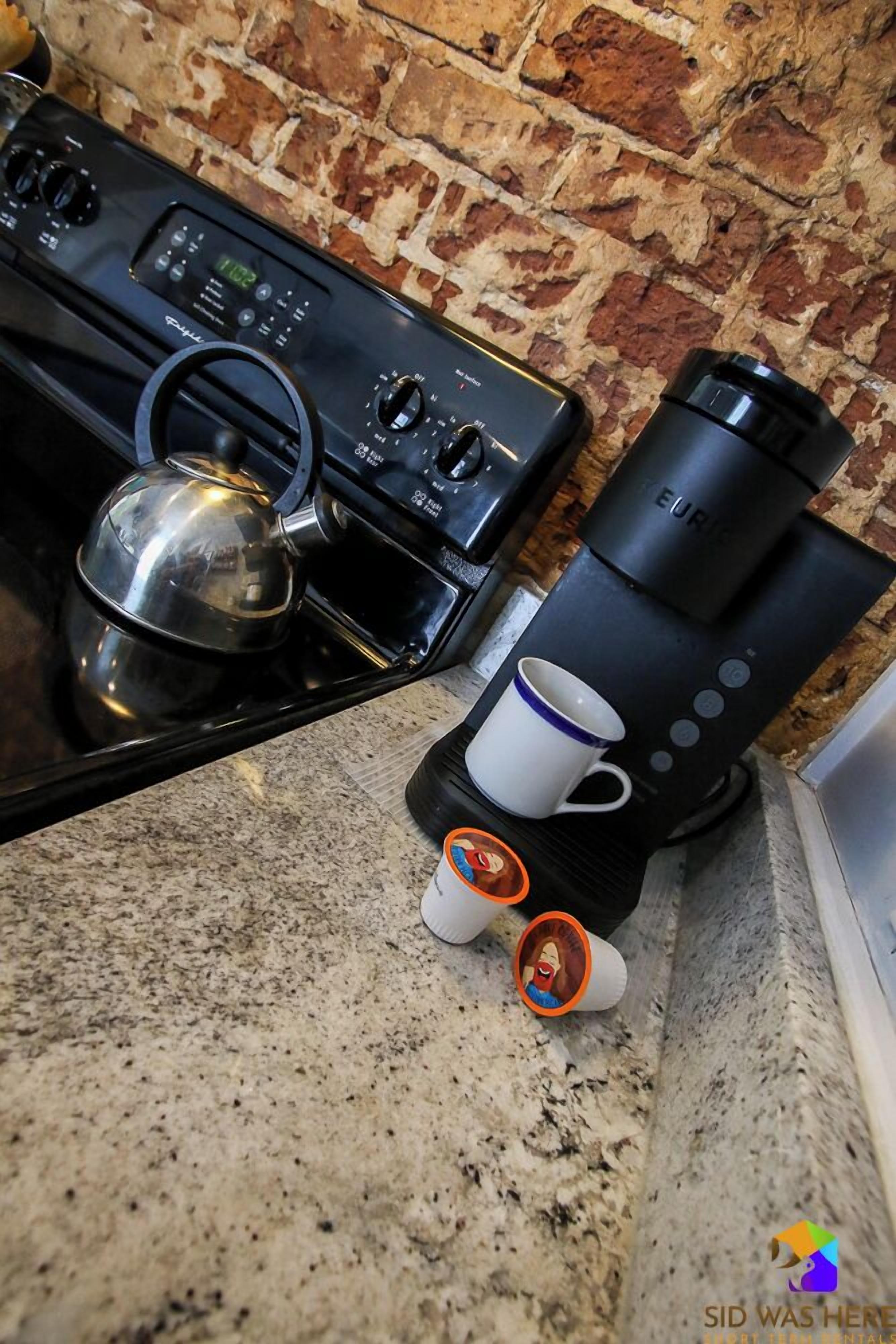 A kitchen with a coffee maker, a kettle, and two cups on the counter.