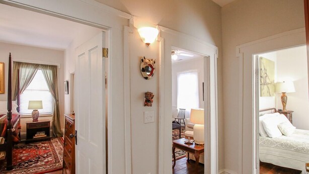 A hallway with a traditional decor, a bed with a white bedspread, and a lamp on a bedside table. - Artist's House Upper Apt Walk to Forsyth (Savannah)